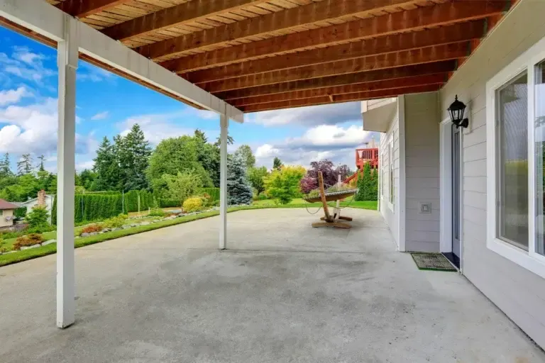 covered back porch on a smooth concrete patio slab beside a garden in Wellington