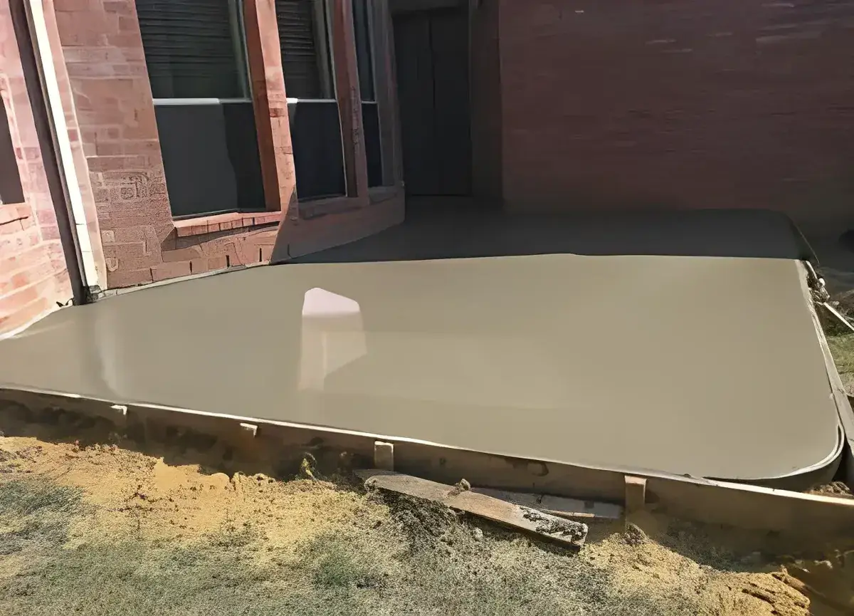 freshly poured smooth concrete patio slab against a brick wall in Riviera Beach