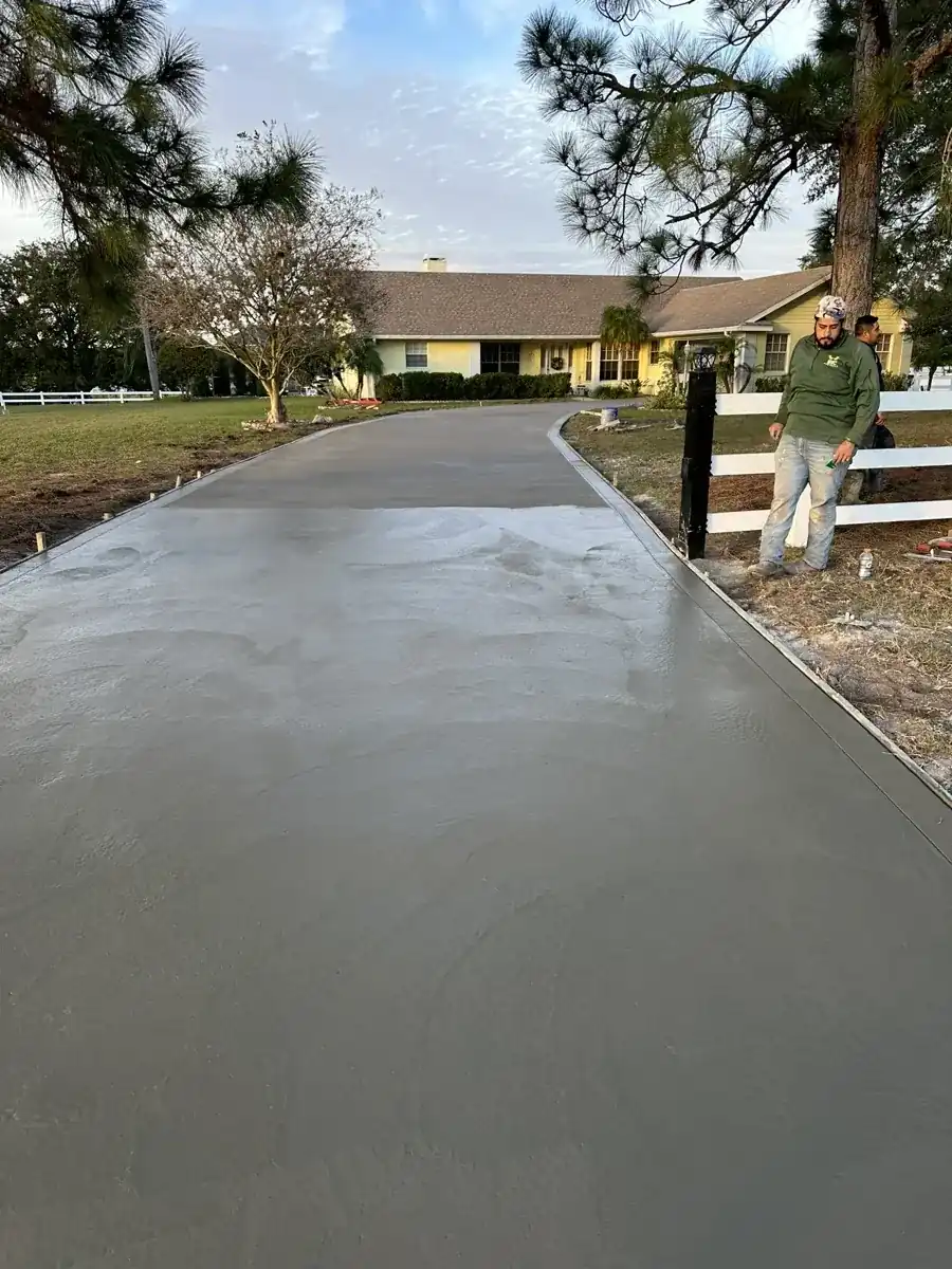 long new concrete driveway curing beside a white rail fence in Palm Beach County