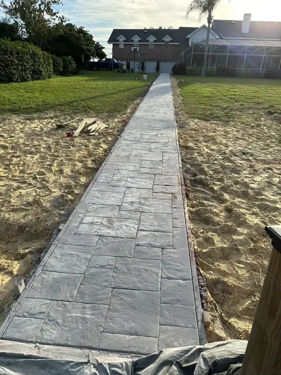 long stamped concrete walkway across a sandy yard to a house in Palm Beach County