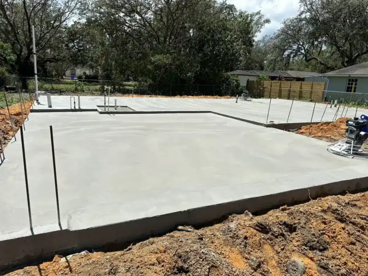 new concrete slab foundation with plumbing stubs on a cleared lot in Boynton Beach