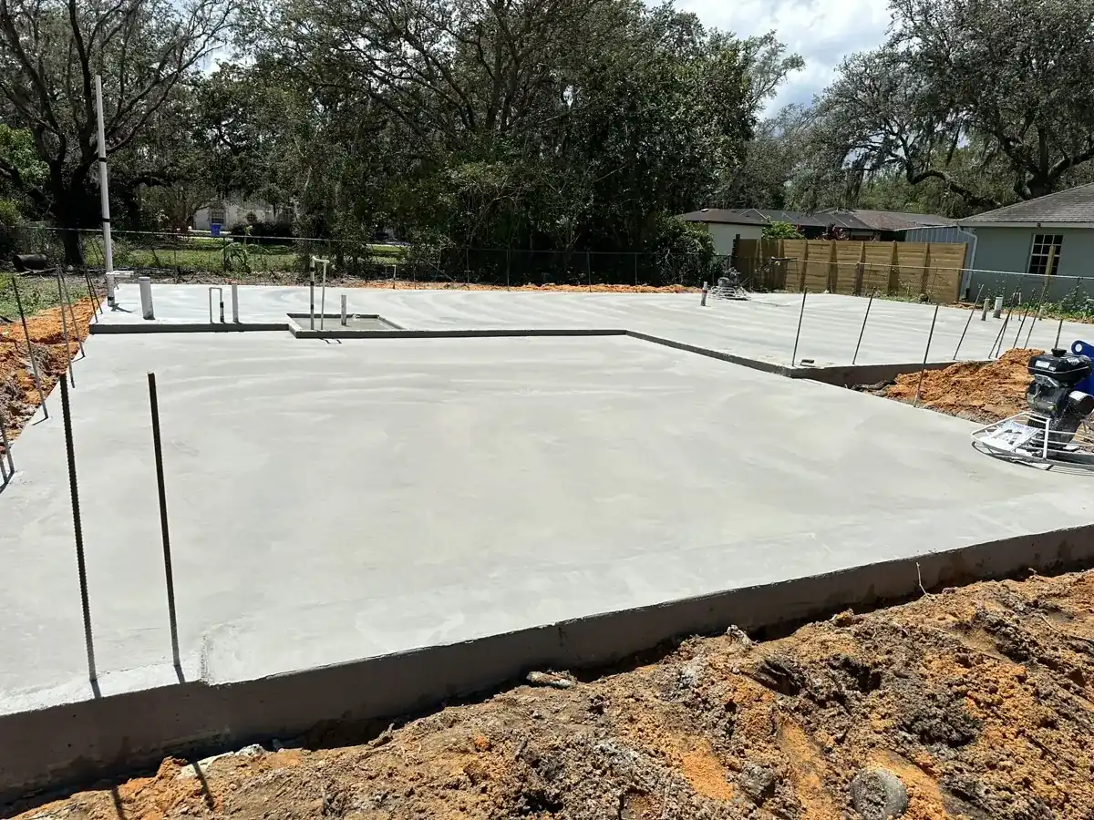 new concrete slab foundation with plumbing stubs on a cleared lot in Wellington